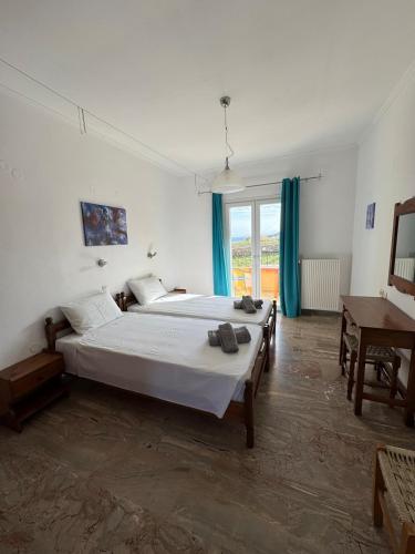 a bedroom with two beds and a table and a window at Agrilia Studios No 5 in Agios Georgios Pagon