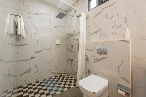 a white bathroom with a toilet and a shower at SaffronStays Ibiza in Nerul