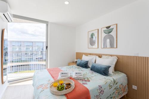 a bedroom with a bed with a bowl of fruit on it at HostWise - Bright Flat with Balcony and Garage in Vila Nova de Gaia
