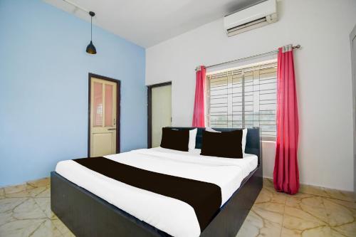 a bedroom with a large bed with red curtains at Super Hotel O Dumduma Near DN Regalia Mall in Bhubaneshwar