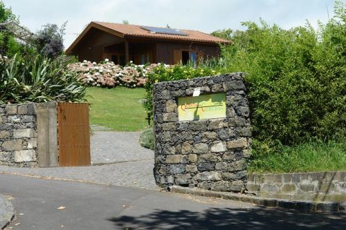a stone wall with a sign in front of a house at Quinta dos Curubas in Vila Franca do Campo