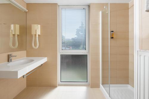a bathroom with a sink and a glass shower at Hotel Albatros Plava Laguna in Poreč