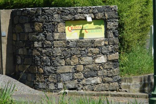 a stone wall with a sign on it at Quinta dos Curubas in Vila Franca do Campo