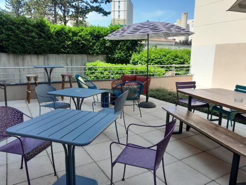 un patio avec tables, chaises et un parasol dans l'établissement Aparthotel Adagio Access Dijon République, à Dijon