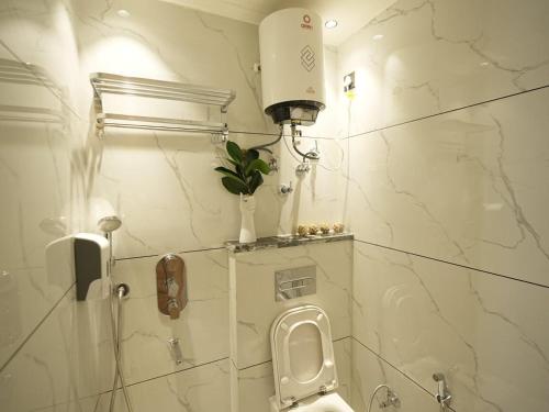a bathroom with a toilet with a plant on a shelf at Orsom Stays Sassy Sector 53 in Gurgaon