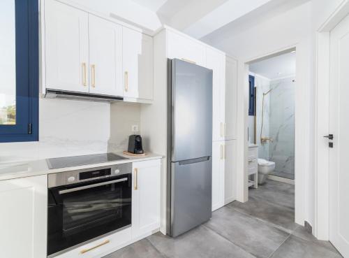 a kitchen with white cabinets and a stainless steel refrigerator at Almira apartment Sivas village in Sívas