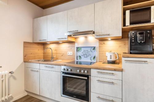 a kitchen with white cabinets and a sink and a microwave at Ferienwohnung Landblick in Homberg
