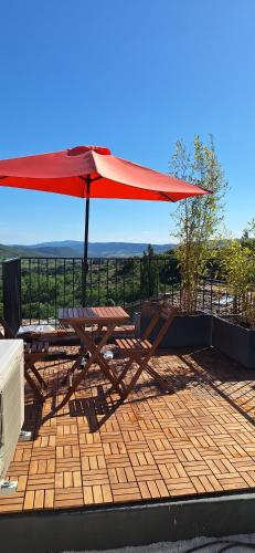 - une table de pique-nique avec un parasol rouge sur la terrasse dans l'établissement Gîte de village 2p, terrasse de toit et jacuzzi privatif, à Aubignas