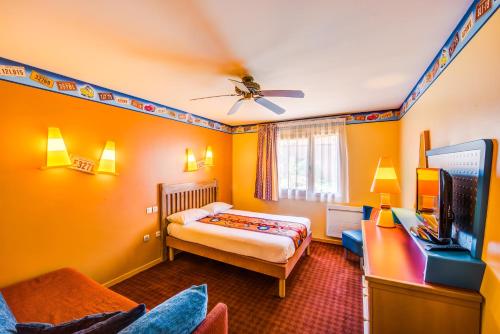 1 dormitorio con paredes de color naranja, 1 cama y TV en Disney Hotel Santa Fe, en Coupvray