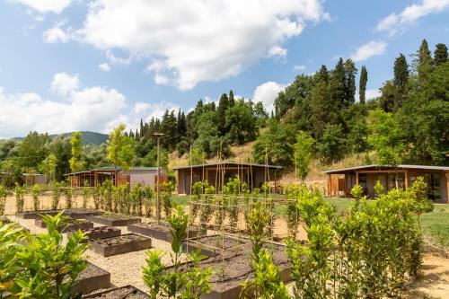 a garden with wooden buildings and trees in the background at Palagina Il Borgo Agricolo in Figline Valdarno