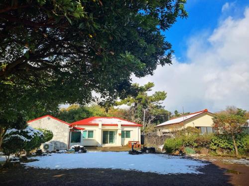 a house with a red roof in the snow at Haenarr Hanok Stay in Mandarin Orchard, 100m from Sea in Seogwipo