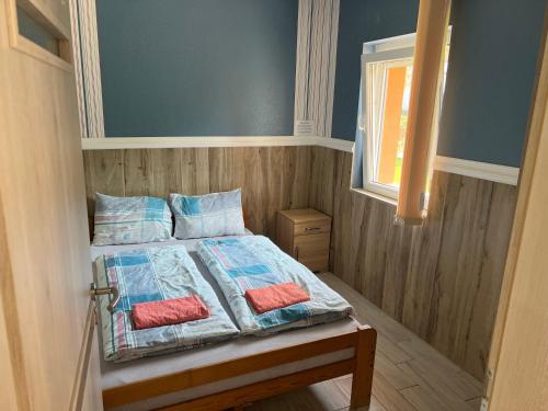 a bedroom with a bed with two pillows and a window at Mediterán Fedett Medencés Apartmanház in Szántód