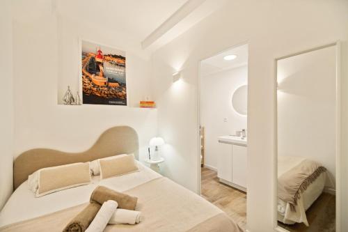 une chambre blanche avec un lit et un miroir dans l'établissement Elegant appt- AC- 1BR 2P - Centre St Tropez, à Saint-Tropez
