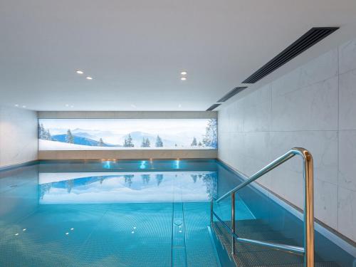 une piscine dans un immeuble avec une grande fenêtre dans l'établissement Charmant Appartement à Rochebrune, Megève - Résidence avec Piscine, Sauna, Hammam et Salle de Sport - FR-1-569-30, à Megève