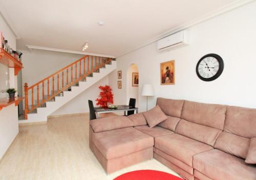 a living room with a couch and a clock on the wall at Costa Orihuela Penthouse with Pool View in Los Altos