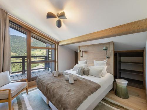 une chambre avec un grand lit et une grande fenêtre dans l'établissement Duplex à Megève avec spa, piscine, salle de sport et cheminée - FR-1-569-32, à Megève