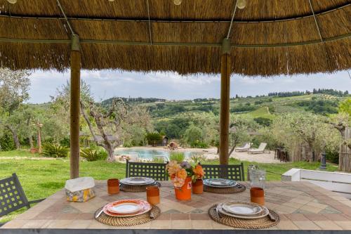 a table under a straw umbrella with a view of a pool at Tenuta Virgilio Colline del Chianti in Tavarnelle in Val di Pesa