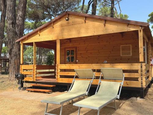 a log cabin with chairs and a grill at ISOLA VERDE Camping Village in Nettuno
