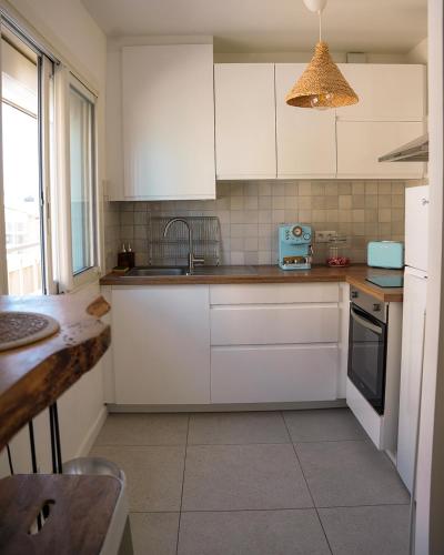 une cuisine avec des armoires blanches et un évier dans l'établissement Au bord de la mer, au Grau-du-Roi