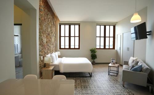 a bedroom with a bed and a couch and a tv at AmazINN Places Casa Fortaleza in Panama City