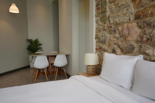a bedroom with two white beds and a stone wall at AmazINN Places Casa Fortaleza in Panama City