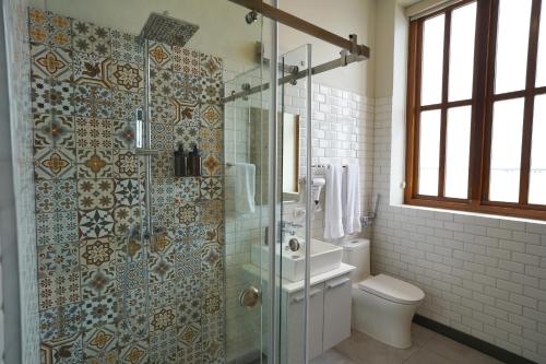 a bathroom with a toilet and a glass shower at AmazINN Places Casa Fortaleza in Panama City
