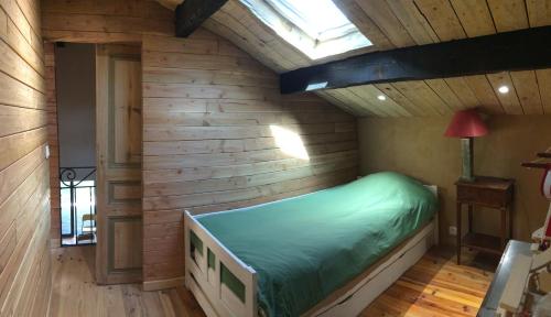 - une chambre avec un lit vert dans un mur en bois dans l'établissement Maison en pleine nature, à Aniane