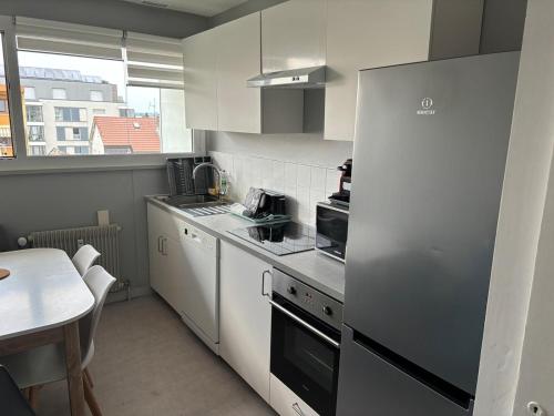 une cuisine avec un réfrigérateur en acier inoxydable et une table dans l'établissement Coloc Cursat I Green Room, à Annemasse