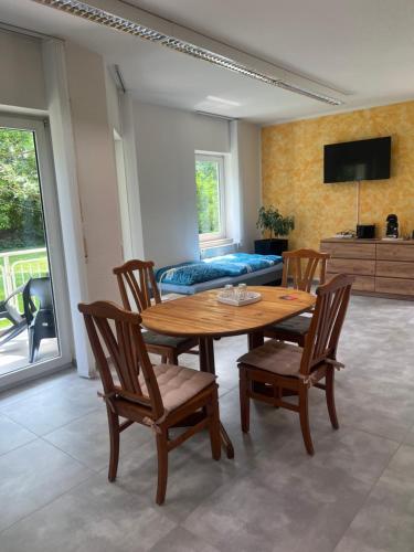een woonkamer met een tafel, stoelen en een bed bij Pension Leipzig Ost in Borsdorf