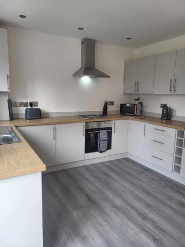 a kitchen with white cabinets and a stove top oven at Modern 3-Bed House in Rotherham, WiFi, Garden & Free Parking in Kimberworth