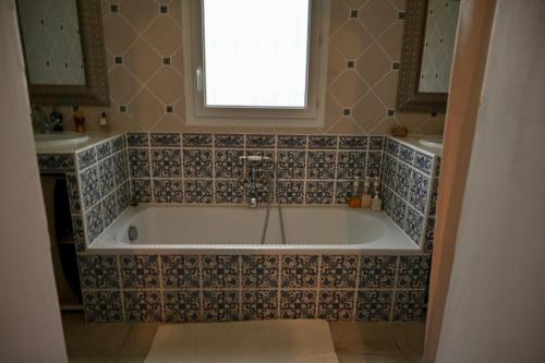 une baignoire dans une salle de bain avec une fenêtre dans l'établissement Villa du Soleil, à Caveirac
