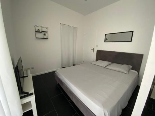 une chambre avec un lit blanc et une télévision dans l'établissement Appartement centre ville Orange, à Orange