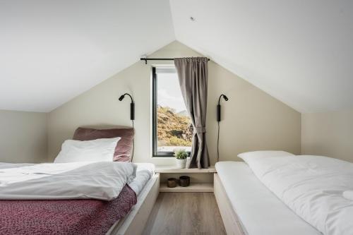 two beds in a room with a window at Lofotendreams - Superior Chalet in Leknes