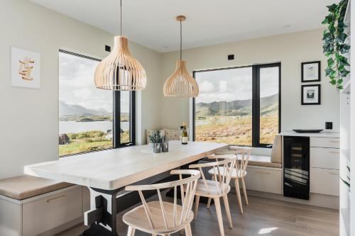 a kitchen with a dining table with chairs and windows at Lofotendreams - Superior Chalet in Leknes