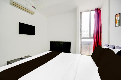 a white bedroom with a bed and a window at Hotel O Panchi Pride in Bhopal