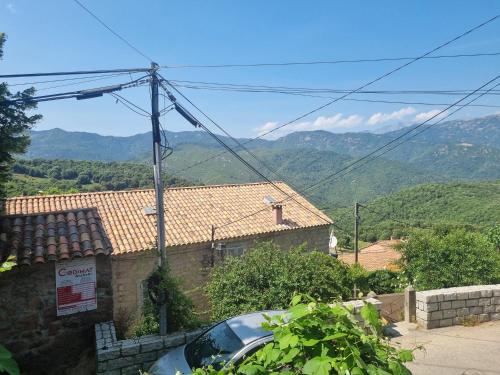 une voiture garée devant une maison avec des montagnes en arrière-plan dans l'établissement maison de village, à Carbuccia