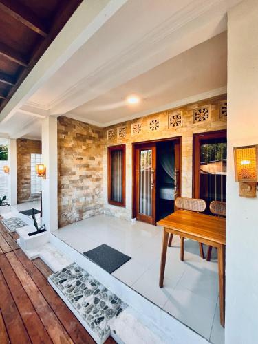 a living room with a wooden table and a stone wall at Lagom Guest House in Gili Air