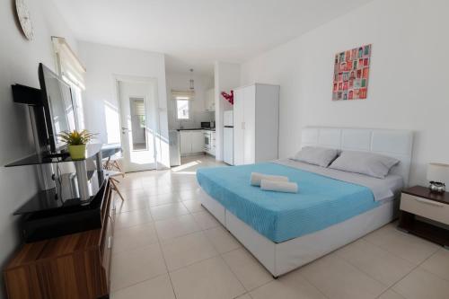 a white bedroom with a blue bed and a kitchen at Студия в жилом комплексе Caesar Beach D1 Flat10 in Boğaz