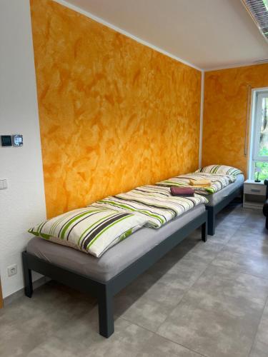 two beds in a room with an orange wall at Pension Leipzig Ost in Borsdorf