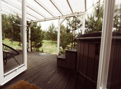 a screened in porch with a hot tub on a deck at Tajnikowo Sekretny Tiny House Anyżek in Łubiana