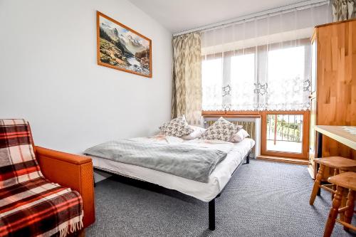 a bedroom with a bed and a chair and a window at U Lańdy in Poronin