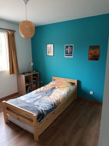 une chambre avec un lit avec un mur bleu dans l'établissement Beach house, à Vensac