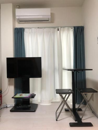 a living room with a flat screen tv and two chairs at 桜屋Sakuraya201 in Tokyo