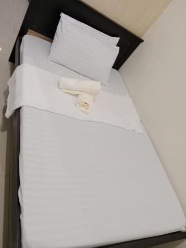 a bed with white sheets and pillows on it at Alyssa Sea Residence MOA condotel in Manila