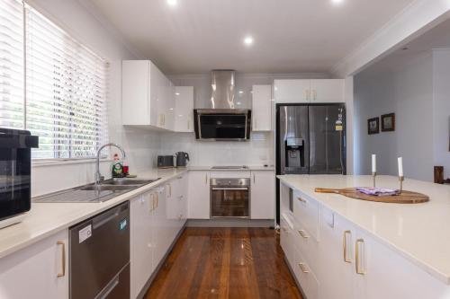 a kitchen with white cabinets and a wooden floor at Zen Escape Guest House " Location 2" - Zen Garden Tiny Home, Nooky Studio, Chillax Rest in Brisbane