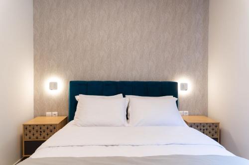 a bed with a blue headboard and white pillows at Zen Luxury Apartments in Xanthi