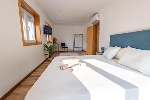 a bedroom with a large white bed with a blue headboard at Cantinho da Estação in Bragança
