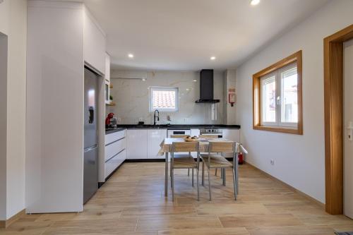 a kitchen with white cabinets and a table and chairs at Cantinho da Estação in Bragança