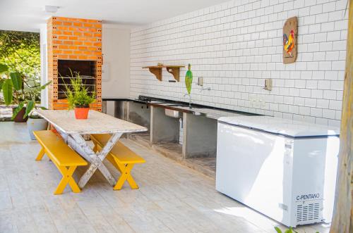 a kitchen with a table and yellow chairs and a refrigerator at Casa c Wifi, churrasq, pisc, redario, Pet friendly in Benfica