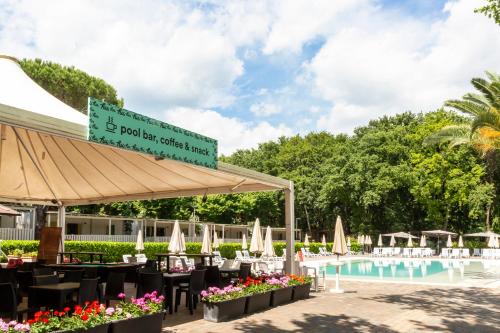 a restaurant with tables and chairs next to a pool at hu I Pini village in Fiano Romano